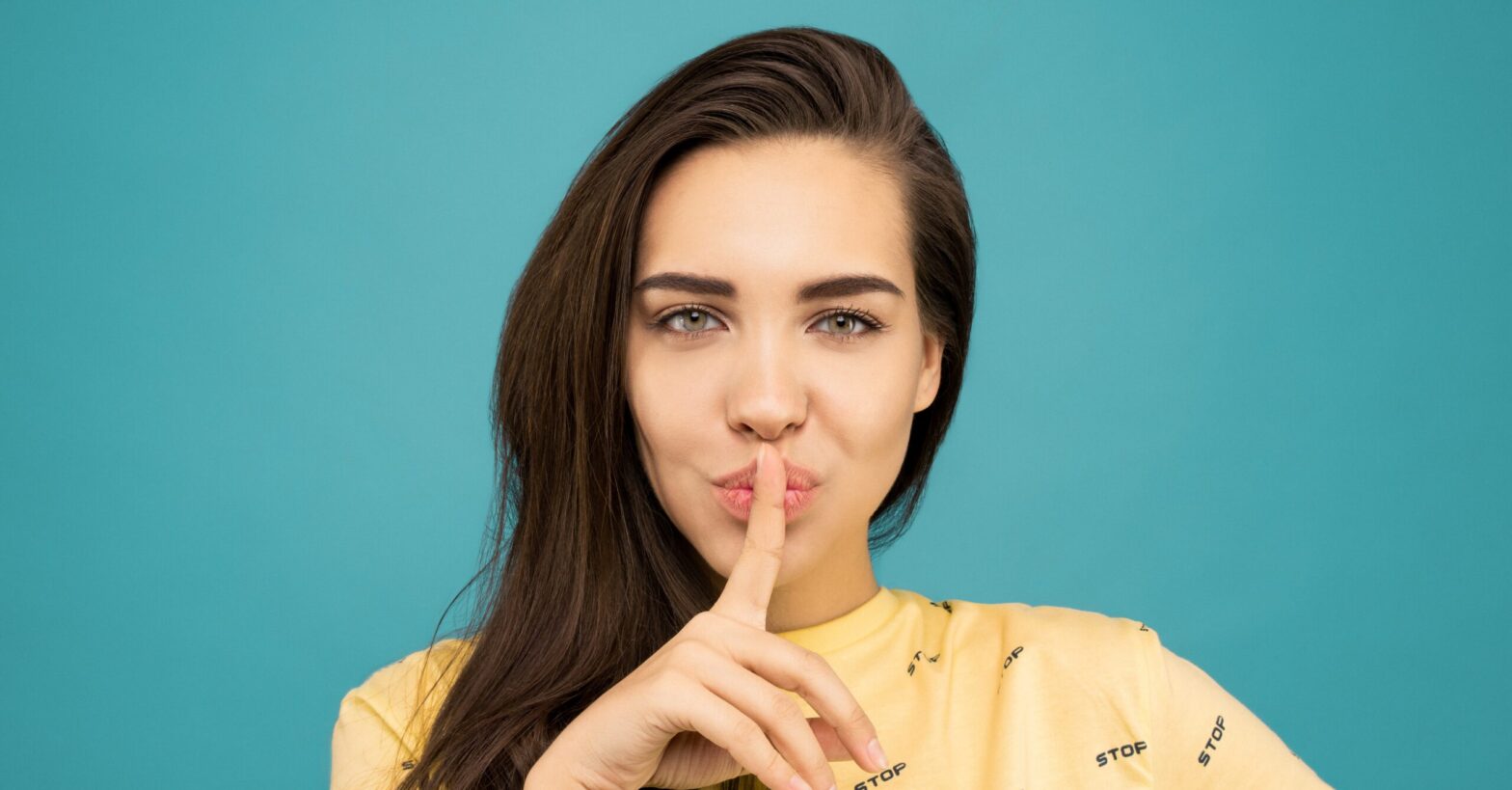 Woman hoding a finger on her mouth as a sign of silence
