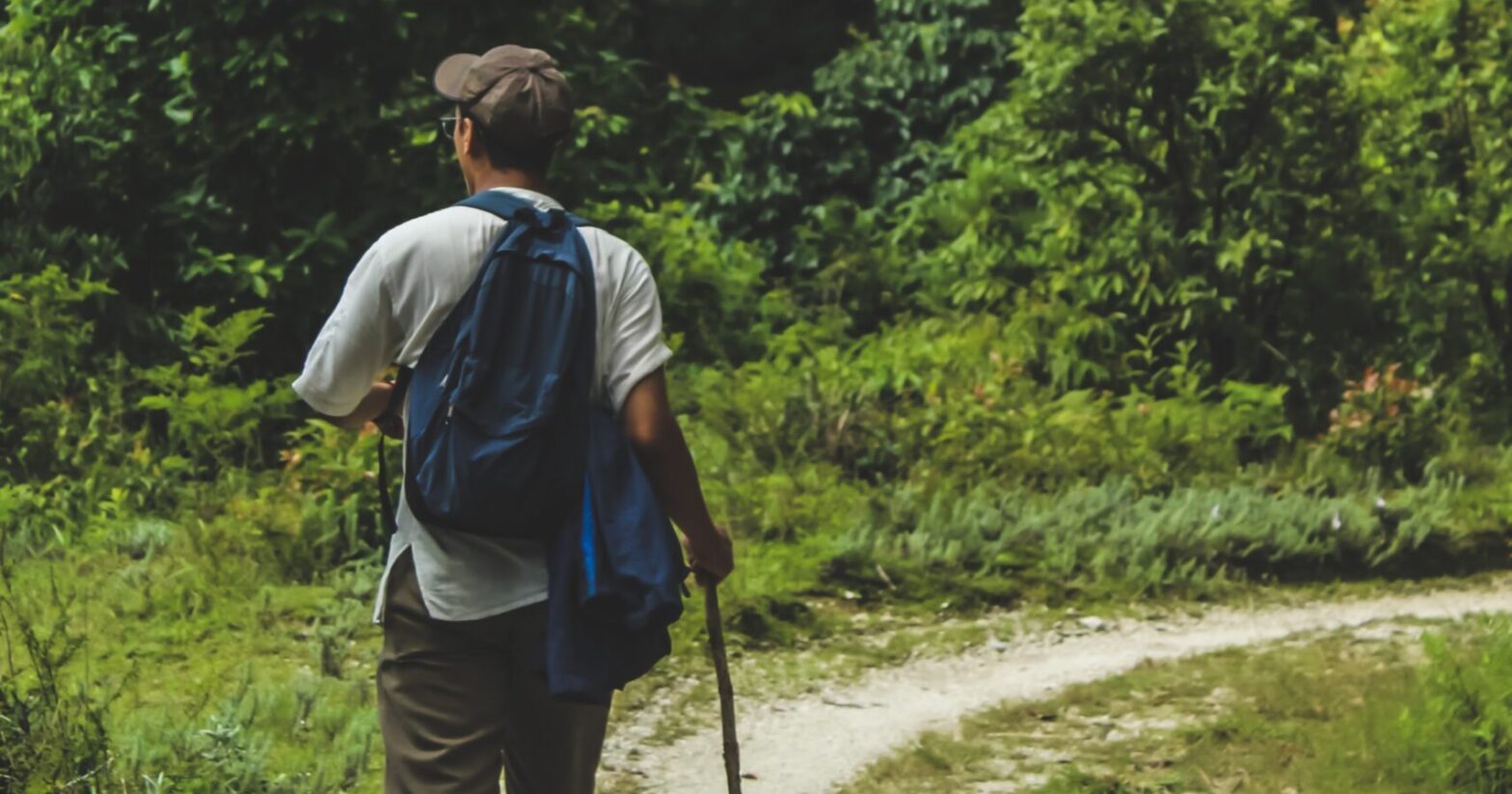 Man walking on trail and carrying a backpack