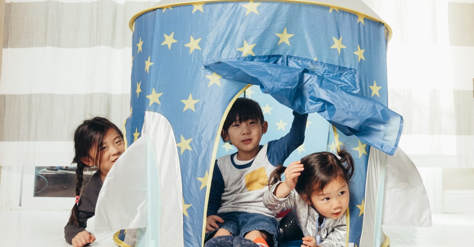Toddlers with a tent doing indoor camping